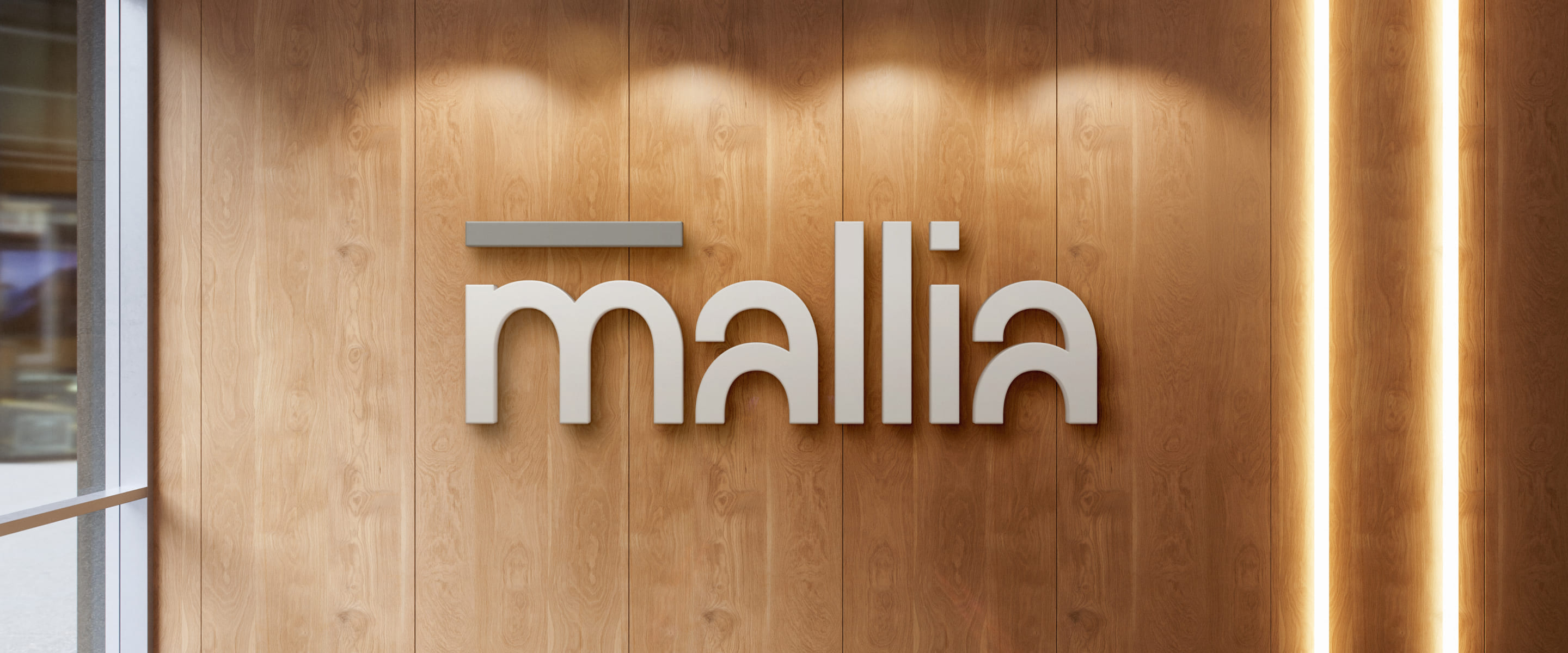 3D word mark “mallia” on a wood panel wall with vertical light strip