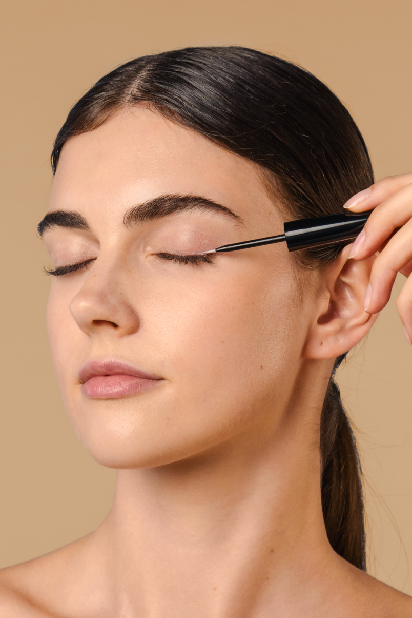 Model strokes 8T3 Lash & Brow Serum along the upper lash line