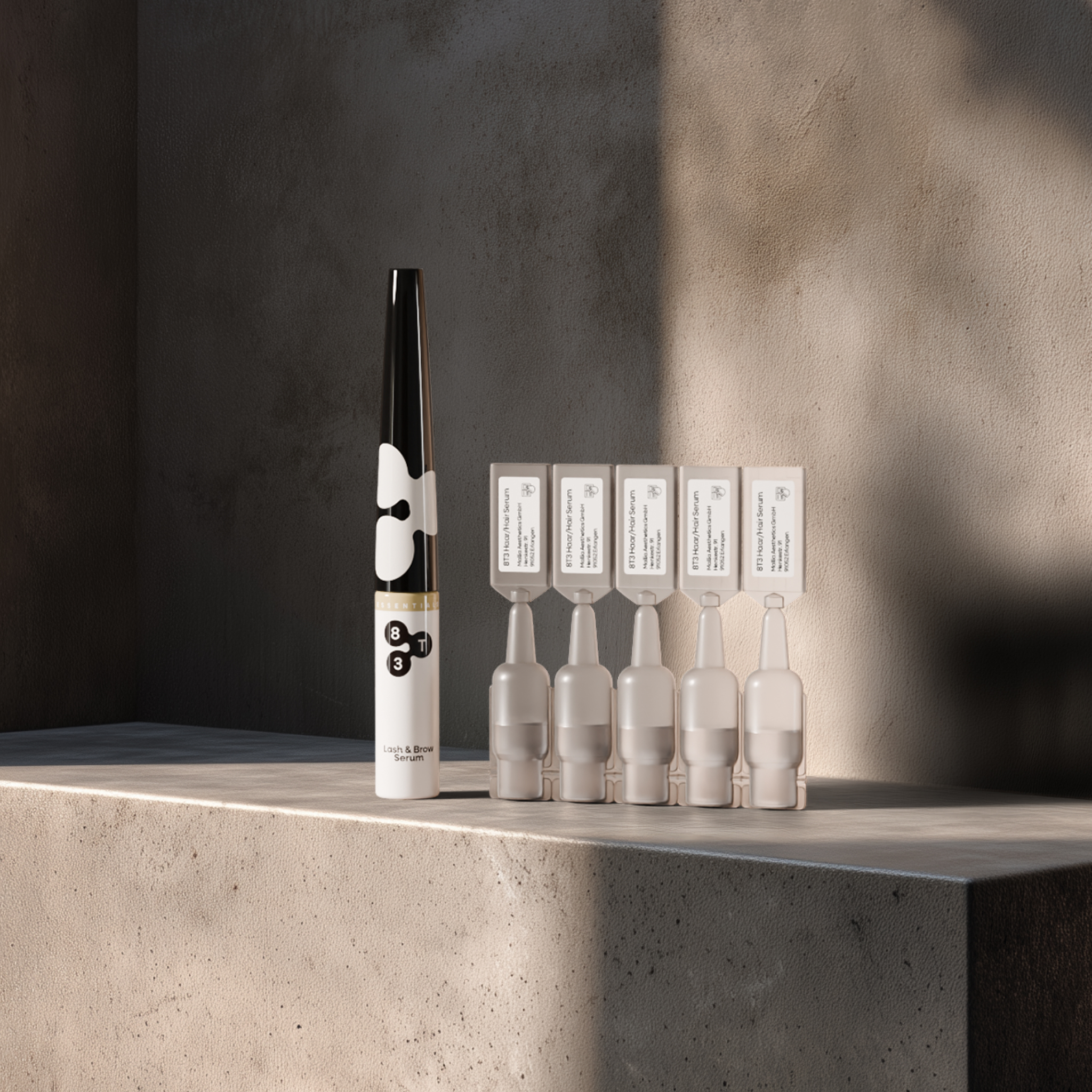 8T3 Lash & Brow Serum next to five 8T3 Hair Serum ampoules on a concrete pedestal