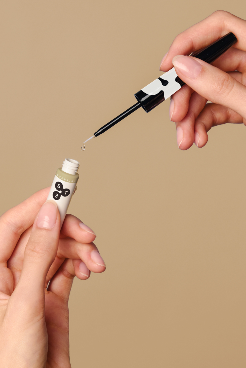 Hand guides fine brush applicator stick with serum drop to opened 8T3 tube